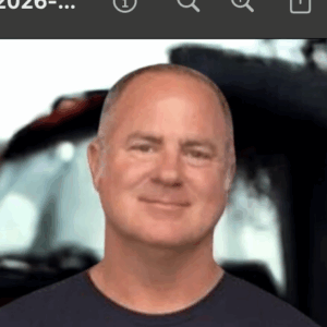 Smiling man in front of a vehicle.