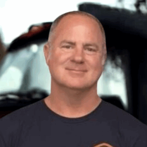 Smiling man in front of a truck.